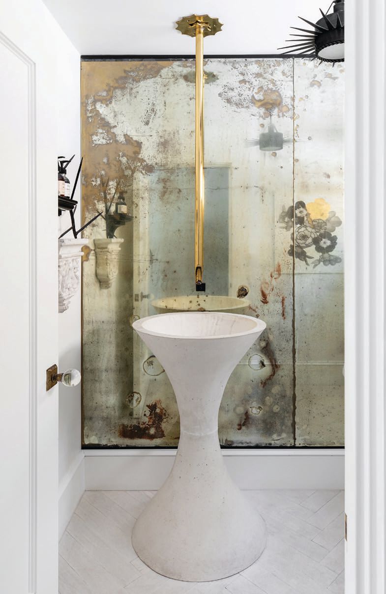 A suspended brass faucet is set against aged mirrored walls in the powder room PHOTO BY: JENNY SIEGWART